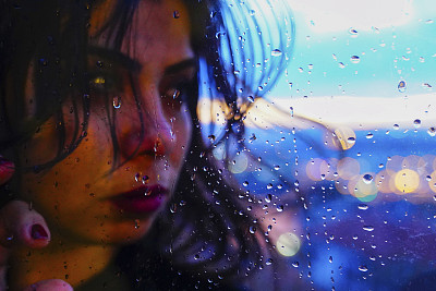 一个悲伤的女人在雨天站在窗前