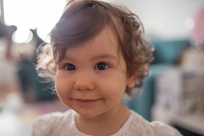 微笑的小女孩在白色的裙子在公寓玩的肖像