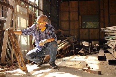 年长的亚洲木匠正在他自己的车库风格的车间修理木框架在退休年龄的爱好与复印空间