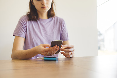 一个白人女人一边充电一边用手机