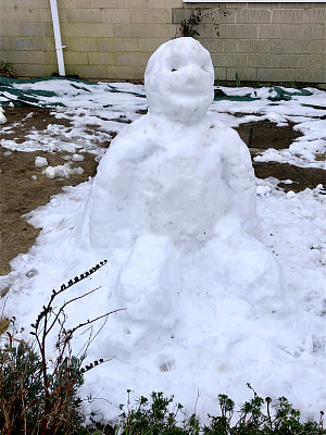 大雪人的形象在柏油马路上，旁边的木栅栏，冬天的景象