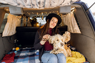 年轻时髦的女人在一辆旧货车里拥抱漂亮的西班牙猎犬