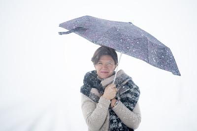 一个女人在寒冷的雪地里撑着伞