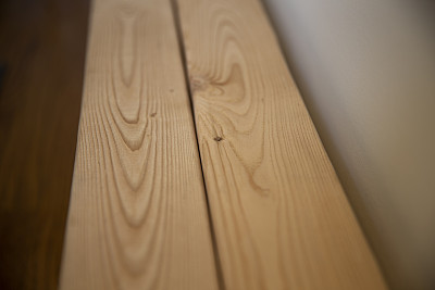 新鲜的木梁。堆放在墙边的木材。未经处理的木梁表面