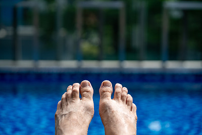 男子赤裸的脚对游泳池的特写。注意大脚趾