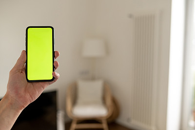 手握黑色手机与空白绿色屏幕和背景现代室内模型图像