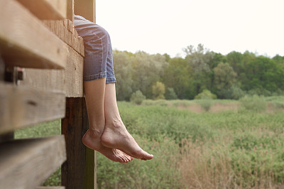 光脚女人坐在木码头上。缓解腿部疲劳。预防静脉曲张的理念