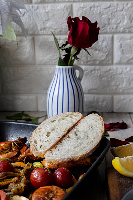 家庭美食:玫瑰，酸面包和烤虾在餐桌上
