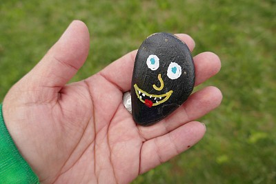 傻笑的脸画在善良的岩石上，握在女人的手里