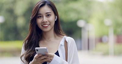 一名亚洲女性在城市街道上使用智能手机