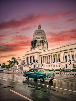 绿色老爷车行驶在El Capitolio前日落，哈瓦那，古巴