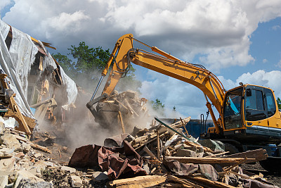 拆除旧建筑的过程。挖掘机打破房子。为新发展而拆除破旧房屋