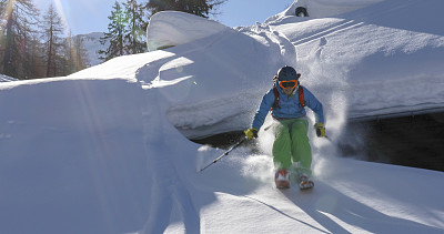 偏远地区的滑雪者从被雪覆盖的岩石上滑下来