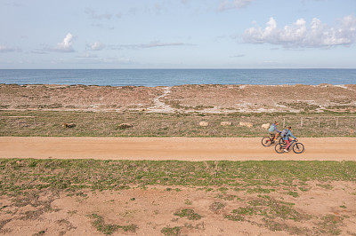无人机拍摄的两个人在海岸线上骑自行车