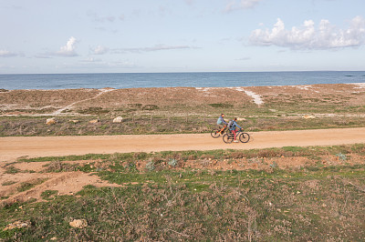 无人机拍摄的两个人在海岸线上骑自行车