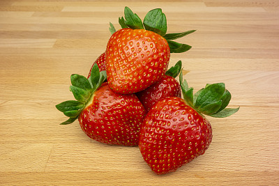 摆在厨房木板上的鲜亮多汁的草莓令人垂涎欲滴