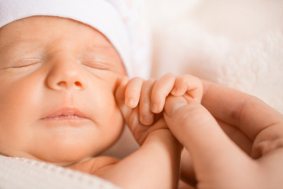 刚出生的婴儿把一根手指放在妈妈的手上。小男孩在睡觉