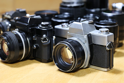 两个单镜头反射相机排成一排，后面还有一个镜头排成一排