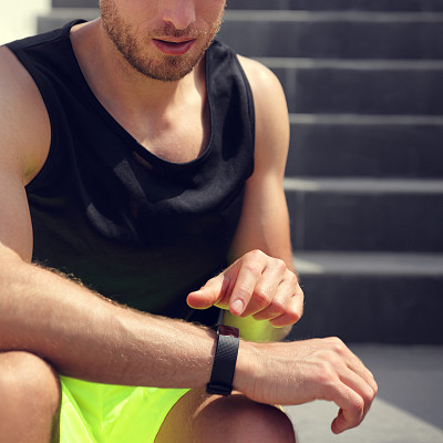 智能手表健身男在楼梯上跑步锻炼前触摸运动手表。手腕和手的特写