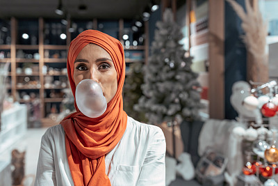 中期成年穆斯林妇女嚼口香糖和做大气球