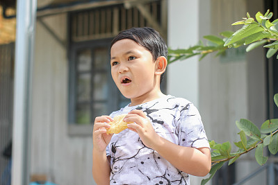 男孩站在前屋吃面包