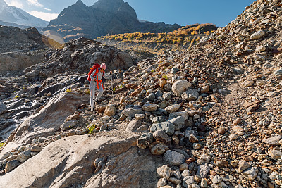 背着背包的女旅行者在山上徒步旅行。游览山与岩石和石头