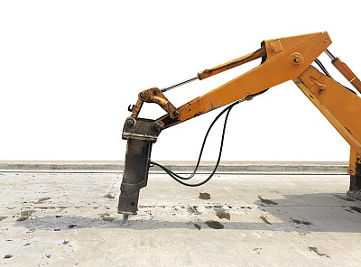 挖掘机开挖混凝土路面进行修补。大型气动锤安装在液压臂上的一种施工设备。施工车辆修理道路。手提钻钻