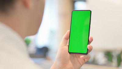 一个年轻人在看带有绿色色度屏幕的智能手机
