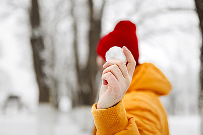 年轻英俊的男子在冬天的一天里，穿着暖和的衣服扔雪球