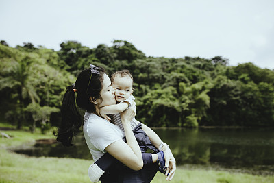 妈妈抱着她的孩子在森林里玩耍