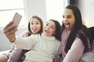 青少年朋友和女孩在家里用智能手机自拍