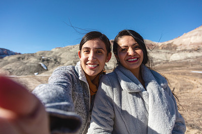 哥伦比亚的美国西班牙裔女性朋友在户外冒险徒步旅行玩在雪添加石头到堆叠的石头Cairn在美国西部沙漠健康的生活方式20 - 55岁照片系列