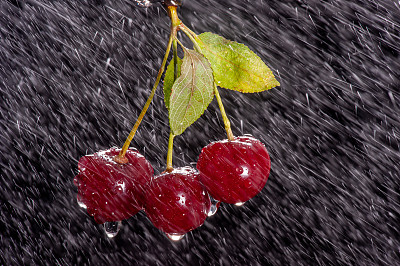 三个樱桃与雨的效果在黑色的背景上