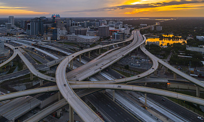 鸟瞰奥兰多市中心，在清晨的日出时分，从拥有高速公路和多个立交桥的大型交通枢纽上空俯瞰。