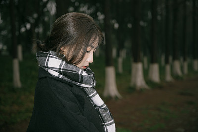 一个孤独的亚洲女孩戴着围巾在一个阴天的湖边