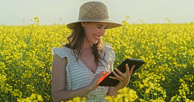 一名年轻女子在花丛中使用数码平板电脑的照片