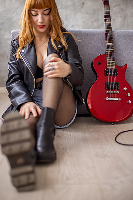 十几岁的女孩坐在地上，旁边放着红色的电吉他