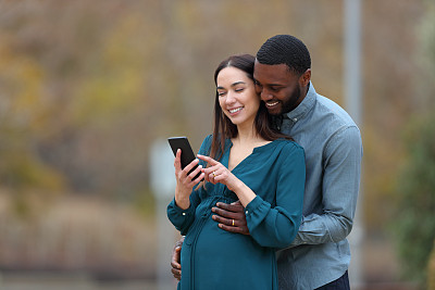 怀孕的妻子和她的丈夫在看智能手机