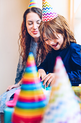 可爱快乐的小女孩和她的妈妈被五颜六色的礼物包围在生日聚会上，傻傻的，微笑着，快乐着