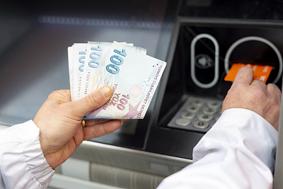 一名妇女用土耳其货币在自动取款机上存钱。