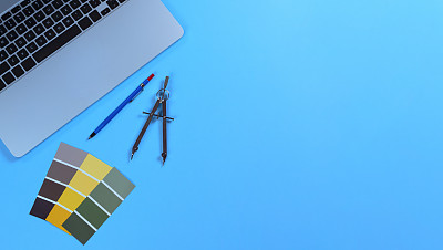 蓝色桌面与建筑师设计工具组成的油漆样本卡和笔记本电脑