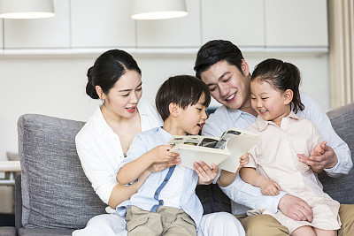 一对父母和他们的两个儿子和女儿一起读儿童故事书-图片