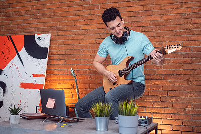 男性吉他手弹奏电吉他，同时从他的家庭音乐工作室练习