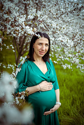 孕妇抱着她的肚子的肖像在自然
