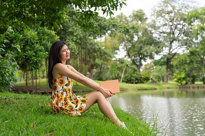 年轻的亚洲女士chill放松和阅读一般的书在公园