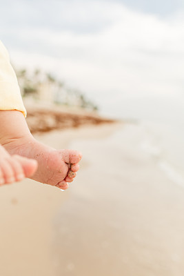 一个6个月大的男婴，12个脚趾在佛罗里达州棕榈滩的金色日出沙滩上