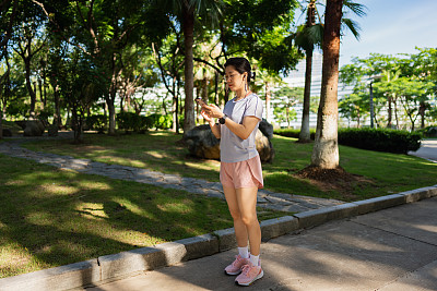 女子在公园散步时使用智能手机