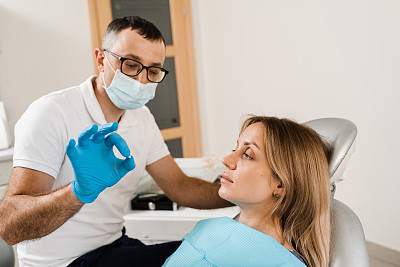 牙科医生在牙科诊所向妇女病人展示种植牙。牙医。向牙医咨询植牙及美白事宜。