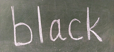 “BLACK”这个词用手写在绿色的学校黑板上。黑色的颜色。打印信件