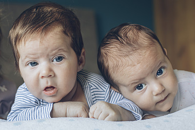 可爱的异卵双胞胎宝宝，弟弟和妹妹，躺在他们的肚子上